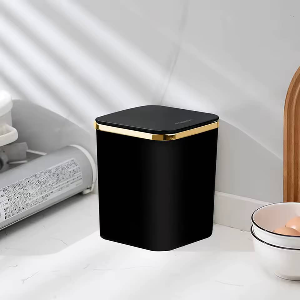 Black small luxury waste bin with gold border placed on marble bathroom countertop